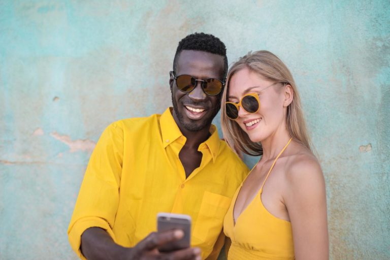 A young smiling couple wearing yellow pulls up content from a brand's voice search strategy.