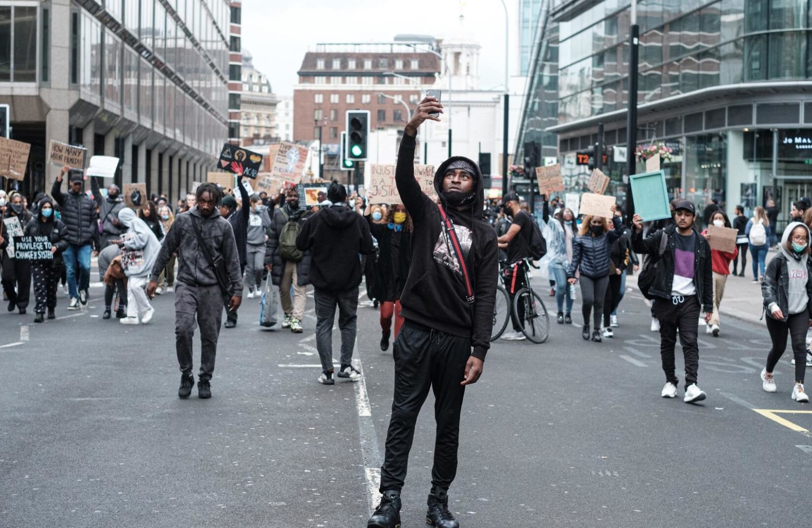 Man facing camera photographs the crowd behind him at a Black Lives Matter protest.