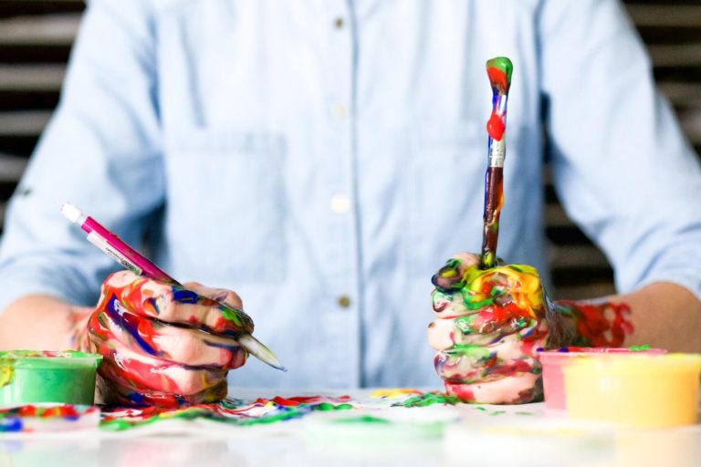person holding paintbrush and pen