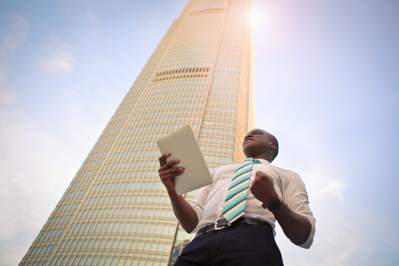 Man holding tablet, standing in front of skyscraper