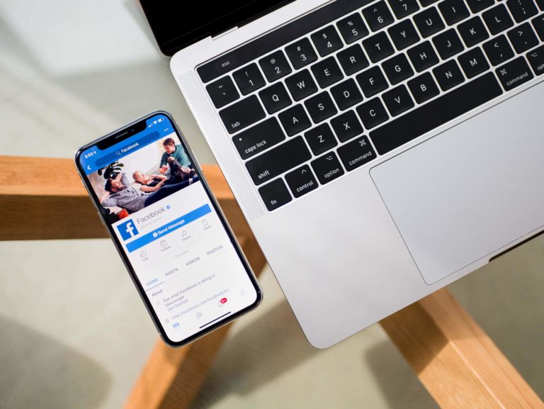 Marketer on laptop typing a caption on a Facebook business page.