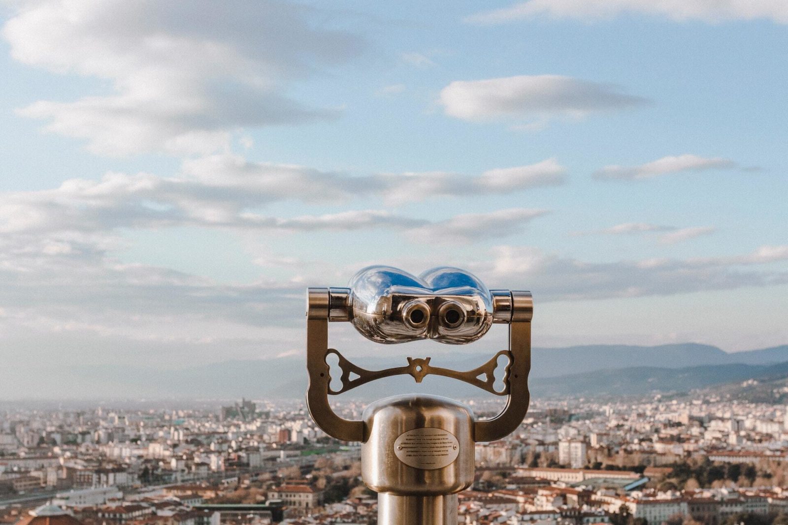 Binoculars overlooking a city on a sunny day.