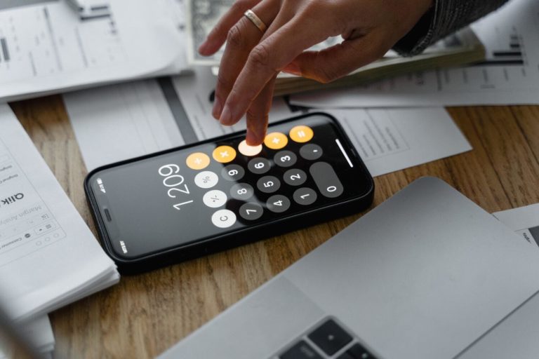 Close-up image of a finger tapping on a smartphone's screen with the calculator app open.