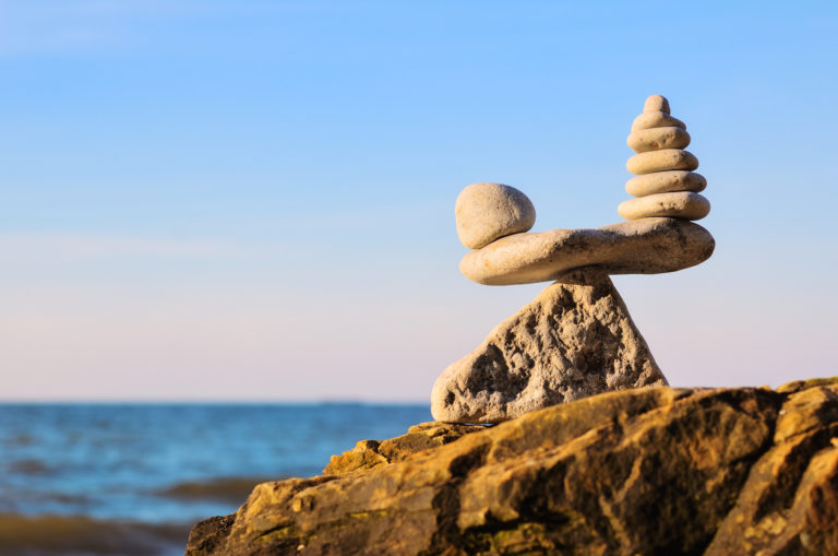One rock balancing on a fulcrum next to a stack of rocks